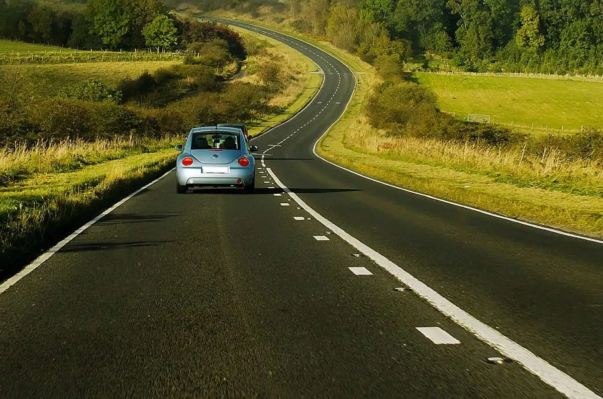 Un coche circulando por una carretera rural sin tráfico