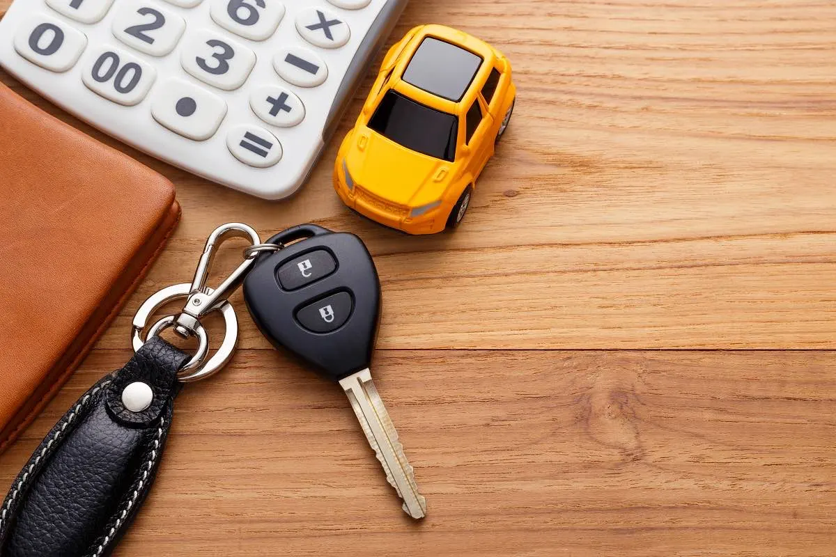 Calculator, wallet, and car keys on a table for adding up monthly interlock costs