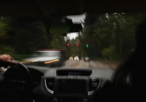 Blurred view from the driver's seat on a wooded road, showing how impairment affects driving