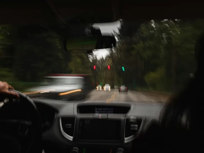 Blurred view from the driver's seat on a wooded road, showing how impairment affects driving